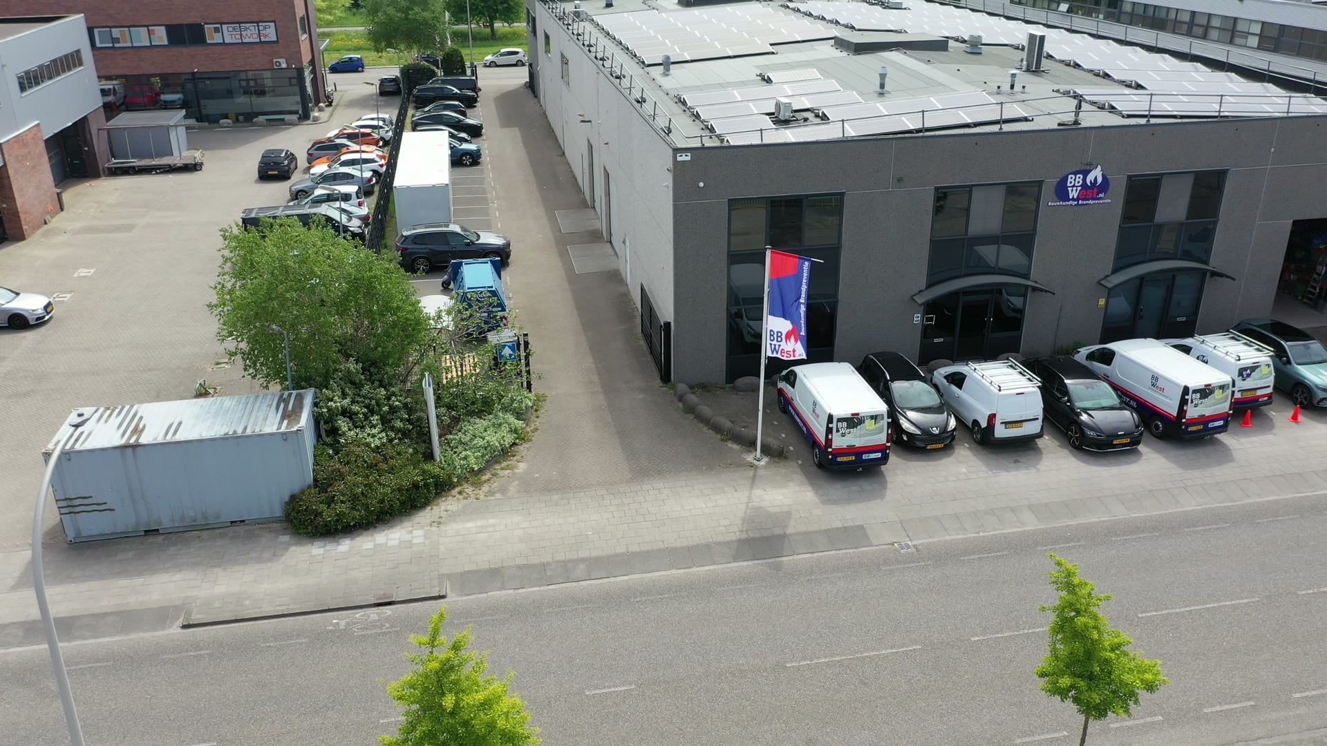 Het pand van BBWest met bedrijfsbussen en vlag