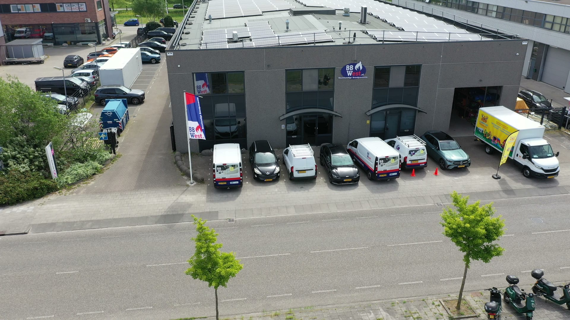 Het pand van BBWest met zonnepanelen en de bedrijfsbussen ervoor